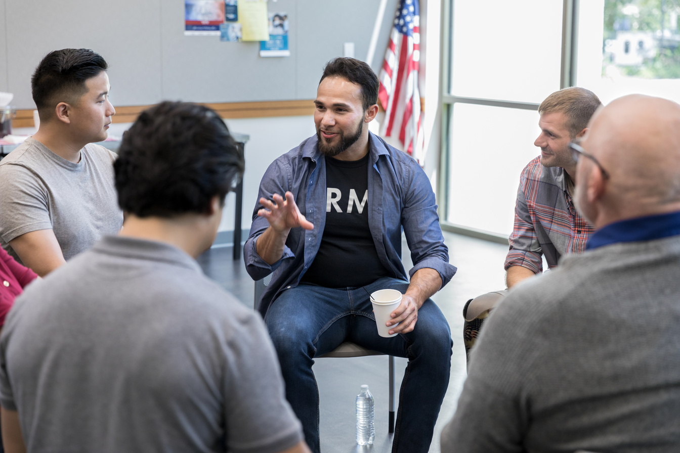 Mid adult Hispanic veteran talks with fellow veterans